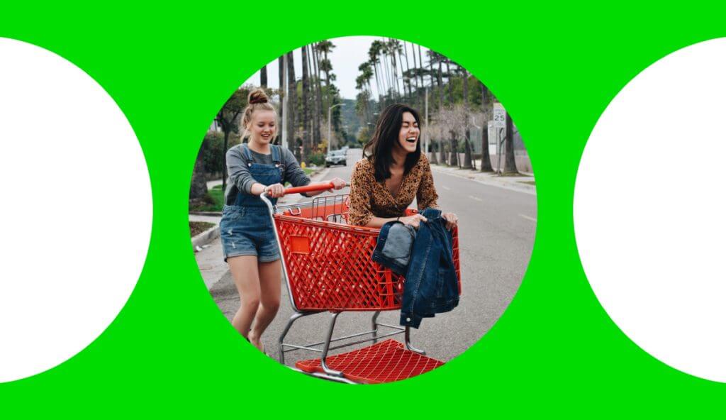 Lady sitting inside a shopping cart getting dragged back to the shopping mart by her friend